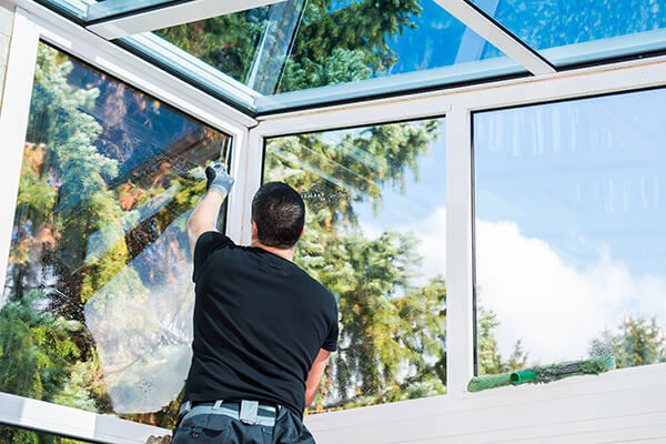 professional in black shirt cleaning windows inside of commercial property