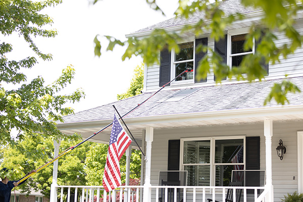 professional cleaning windows on white home with rod-like equipment