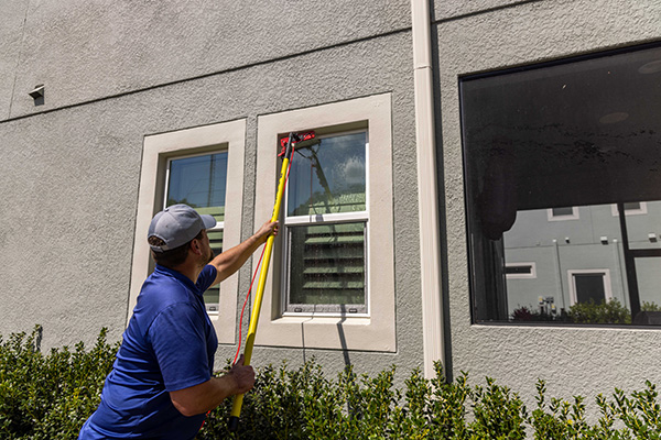 professional in blue shirt using yellow window cleaning brush to clean windows